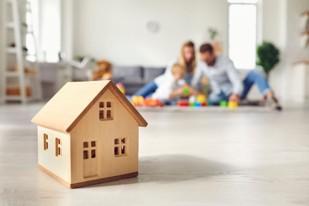 Houten huis met op de achtergrond een blije familie aan het spelen